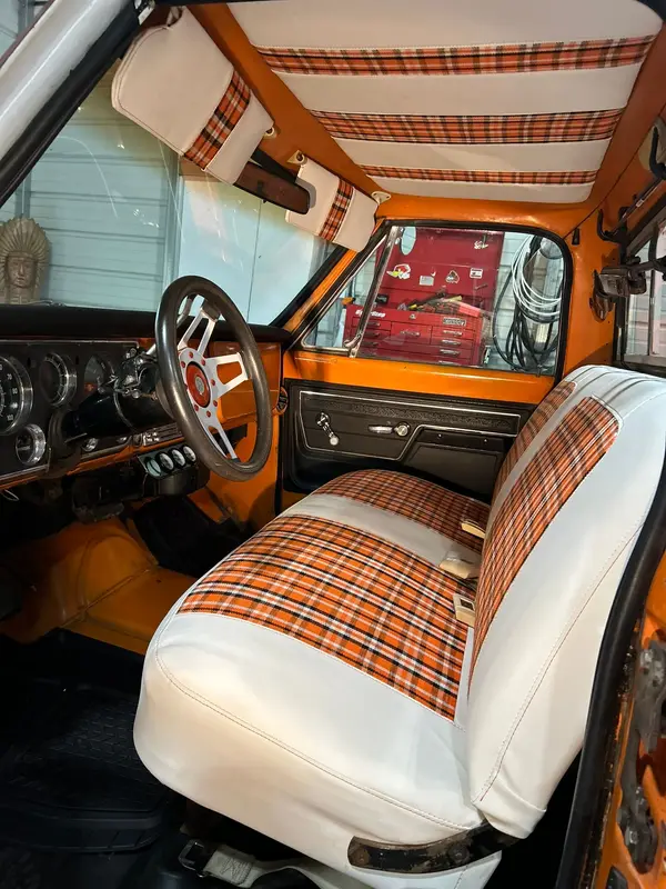 Chevy cab with a white and orange plaid bench seat and striped headliner
