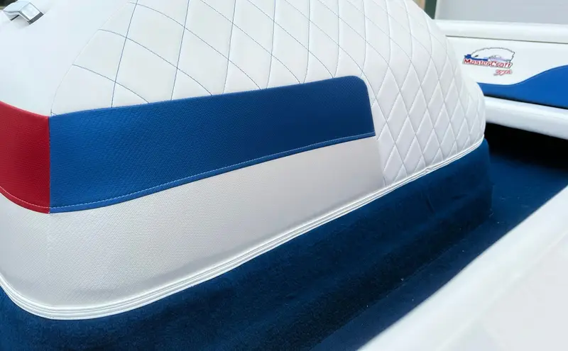 Close-up of the engine cover: blue diamond stitching, red and blue carbon-texture panels and white piping